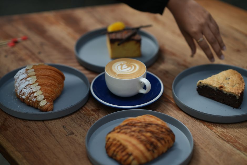 Flat white y pan dulce sobre la mesa de madera